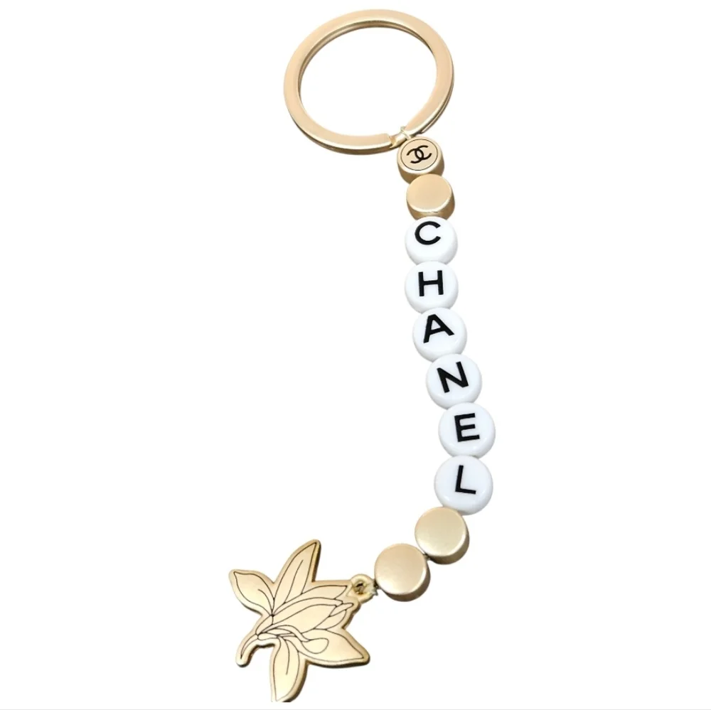 NIB CHANEL Sublimage Gold & White Beaded Keychain with Flower Charm